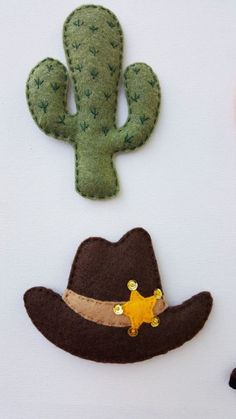 three felt cactus, hat and star brooches on a white table cloth background