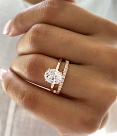 a woman's hand wearing a gold ring with an oval shaped diamond in the center