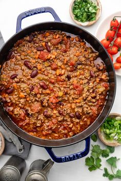 a pot filled with chili and beans next to other food on top of a stove