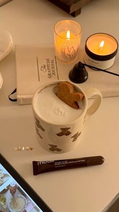 a cup with a piece of bread in it next to a candle and some other items