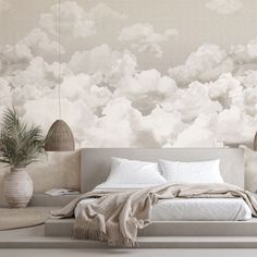 a bedroom with clouds painted on the wall and bed in the foreground, potted plant next to it