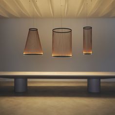 three lamps hanging from the ceiling above a table with a bench in front of it