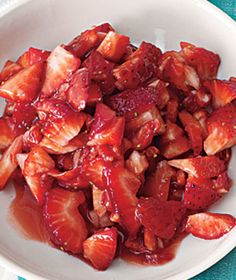 a white bowl filled with sliced strawberries on top of a blue and white table cloth