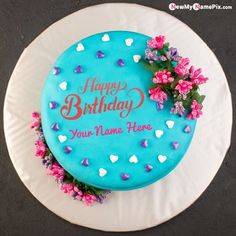 a birthday cake with blue frosting and pink flowers on the top is sitting on a white plate