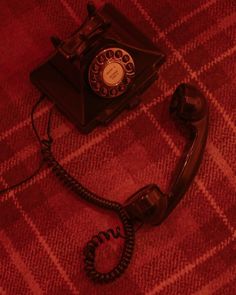 an old fashioned telephone is laying on the floor with its cord still attached to it