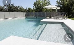 an empty swimming pool with lounge chairs and umbrellas