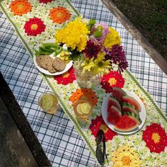 a picnic table with flowers and watermelon slices on it, along with other food items