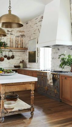 a kitchen with an island in the middle and hanging lights on the wall above it