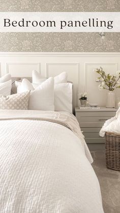 a bed room with a neatly made bed next to a basket filled with pillows and blankets