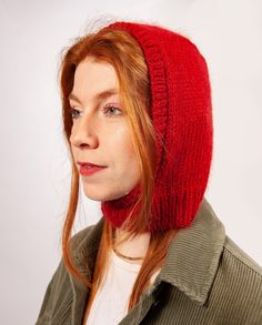 a woman with red hair wearing a knitted hat and looking off to the side