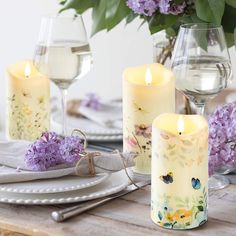 the table is set with candles and flowers in vases next to plates, silverware, and wine glasses