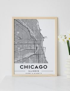 chicago illinois city map framed in a wooden frame next to a vase with white flowers