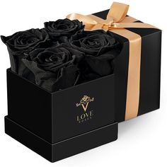 a black box with four roses in it and a gold ribbon around the top that says love