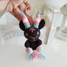 a hand holding a small crocheted keychain with an animal on it