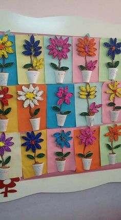 colorful flowers are arranged in vases on a multi - colored wall hanging from the ceiling