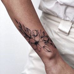 a woman's arm with flowers on it and the wrist is tattooed in black ink