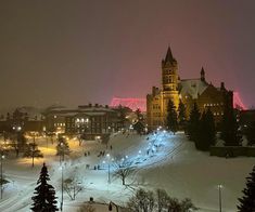 a large building that is lit up in the night with people walking around on it