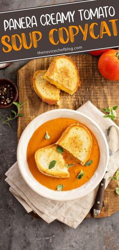 a white bowl filled with soup and toast on top of a wooden cutting board next to tomatoes