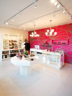 the interior of a store with pink walls and chandeliers hanging from the ceiling