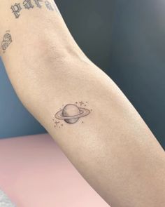 a small saturn tattoo on the left forearm and arm, with stars in the sky