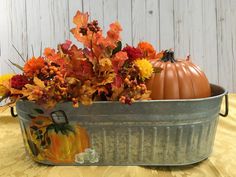 a metal tub filled with flowers and pumpkins