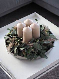 some candles are sitting on a plate with greenery