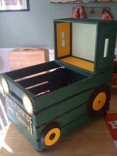 a green toy truck bed sitting on top of a wooden table next to a chair