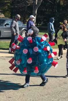 a group of people walking down a street next to a blue ball with red and white decorations on it