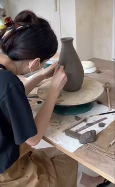 a woman is working on a clay vase