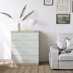 a living room with white furniture and pictures on the wall, including a couch in front of a dresser