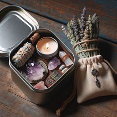 an open tin with candles, rocks and other items in it on a wooden table