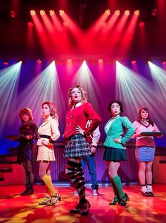 a group of women standing next to each other on top of a stage with spotlights