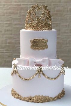 a three tiered cake with gold trimmings and a tiara on top