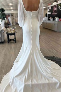 the back of a woman's wedding dress with pearls on it in a store