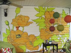 a living room with yellow flowers painted on the wall and green chairs in front of it