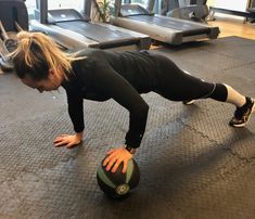 a woman doing push ups with a medicine ball