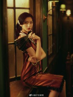 a woman in a red dress holding a fan sitting on a window sill next to a door