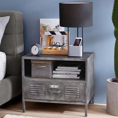 a nightstand with a lamp and pictures on it next to a couch in a living room