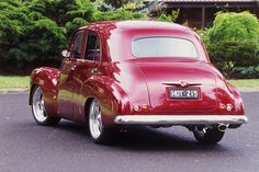 an old red car is parked on the street