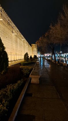 an empty sidewalk next to the water at night