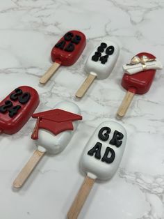 four pops with graduation decorations on them sitting on a marble countertop in front of a white background