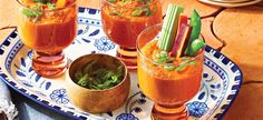 three glasses filled with different types of food on a plate next to another glass full of vegetables