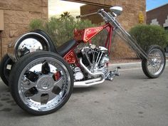 a red motorcycle with chrome rims parked in front of a brown building on the street