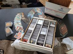 an open box filled with lots of different colored cards on top of a table next to other boxes