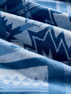 the blue and white blanket has an arrow design on it's side, while another pattern is in the background