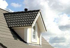 the roof of a house with a dormer window and gutter running down it