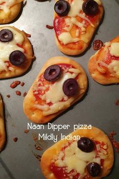 mini pizzas with olives and cheese are on a baking sheet, ready to be eaten