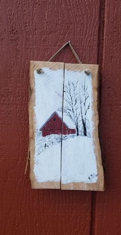 a red barn in the snow is hanging on a wall