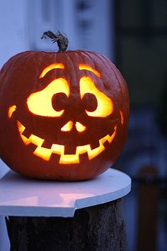 a carved pumpkin sitting on top of a wooden post