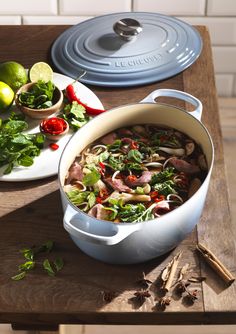 a large pot filled with food next to a plate of vegetables and lemon wedges